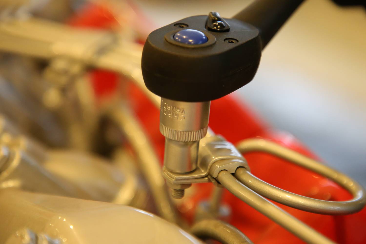 A torque wrench tightens a screw on a mechanical component. Focused view on the tool and the connection.