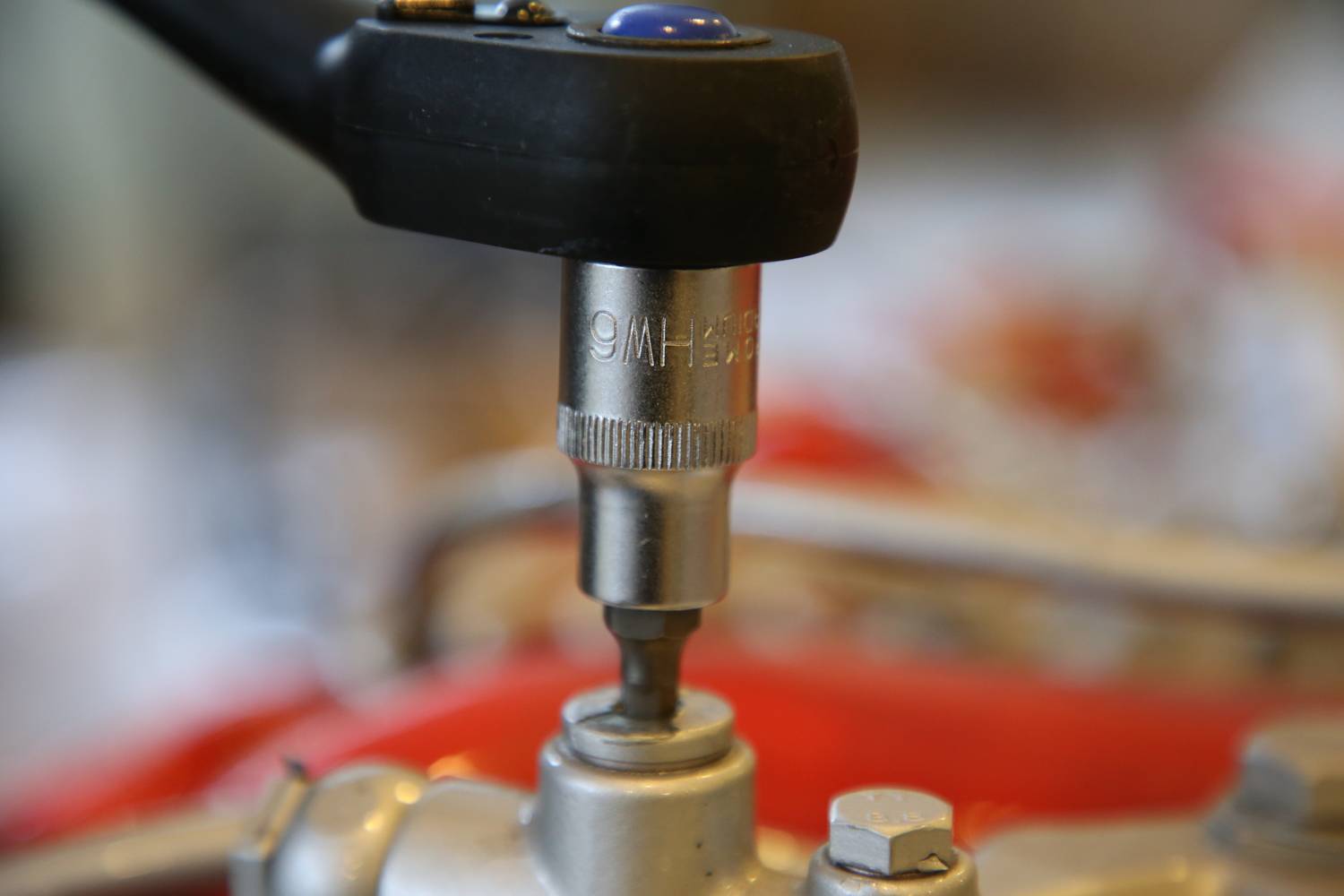 Close-up of a socket wrench working on a screw, likely during a repair or maintenance task.