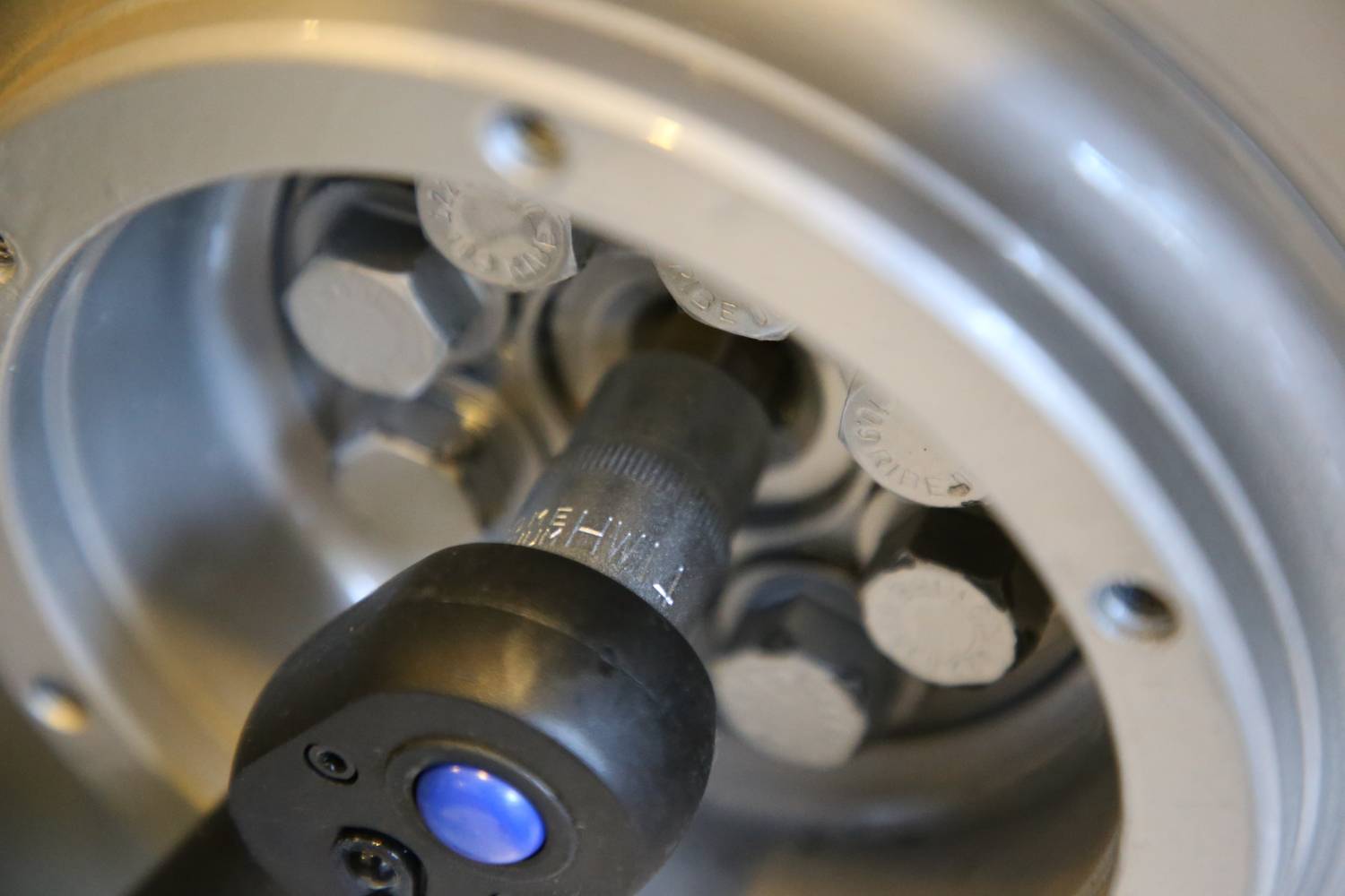 Close-up of a spanner working on a silver machine screw. Focused on mechanical details.