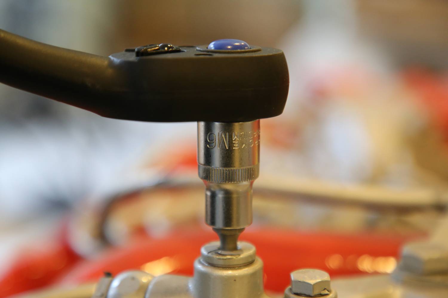 A torque wrench tightens a screw to ensure precise tension. Background blurred, focus on tool and screw.