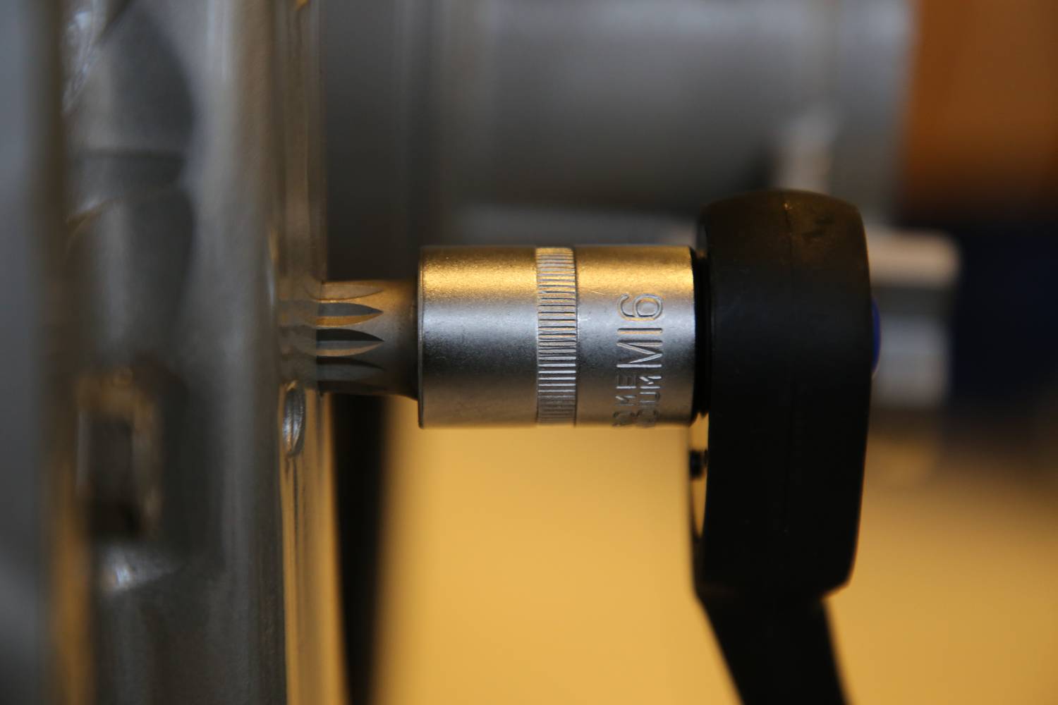 Close-up of a tool with a Torx bit attachment, being twisted into a metal screw. Screw and tool in focus.