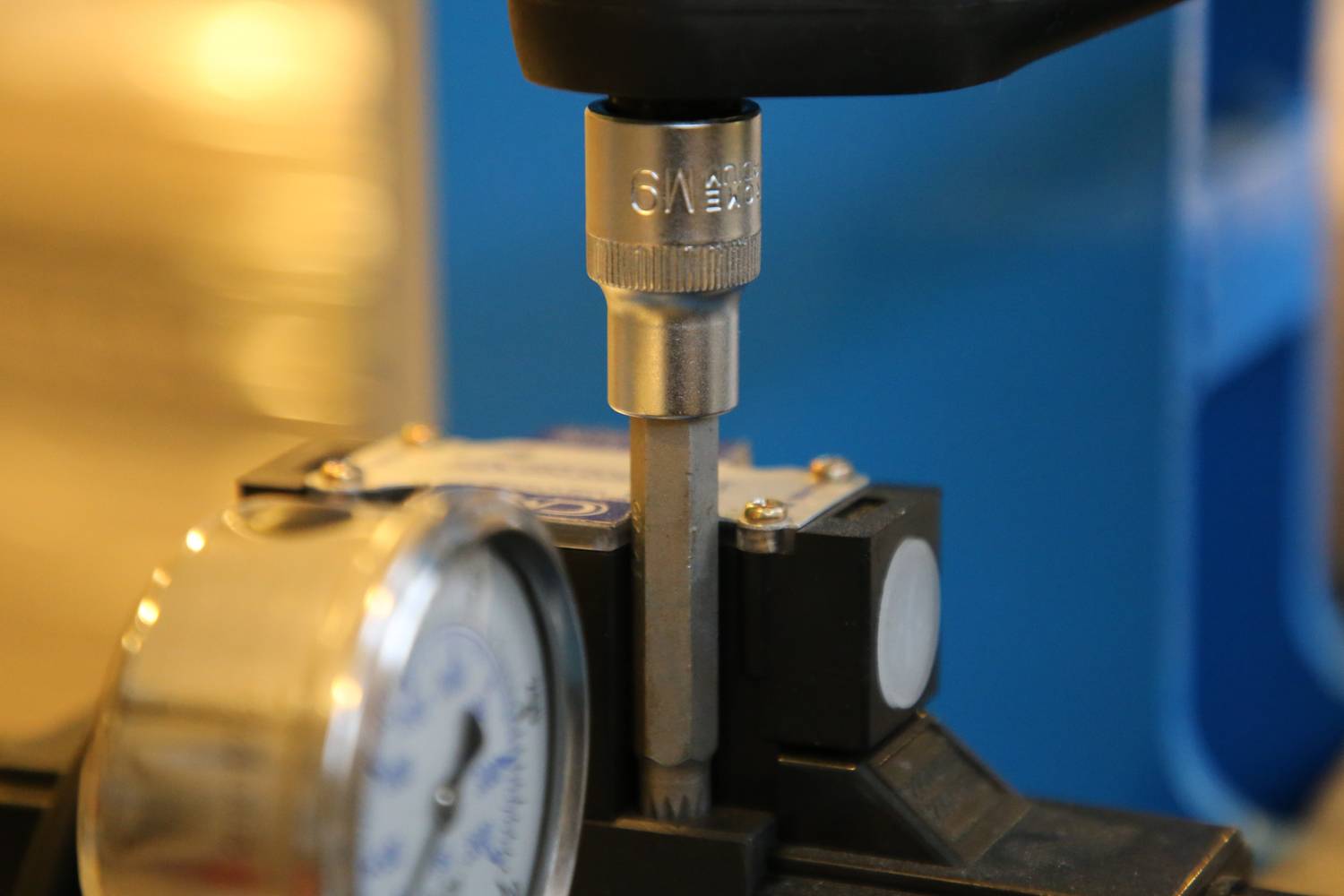 A torque wrench is connected to a device to perform precise measurements. Digital display shows the measured value.