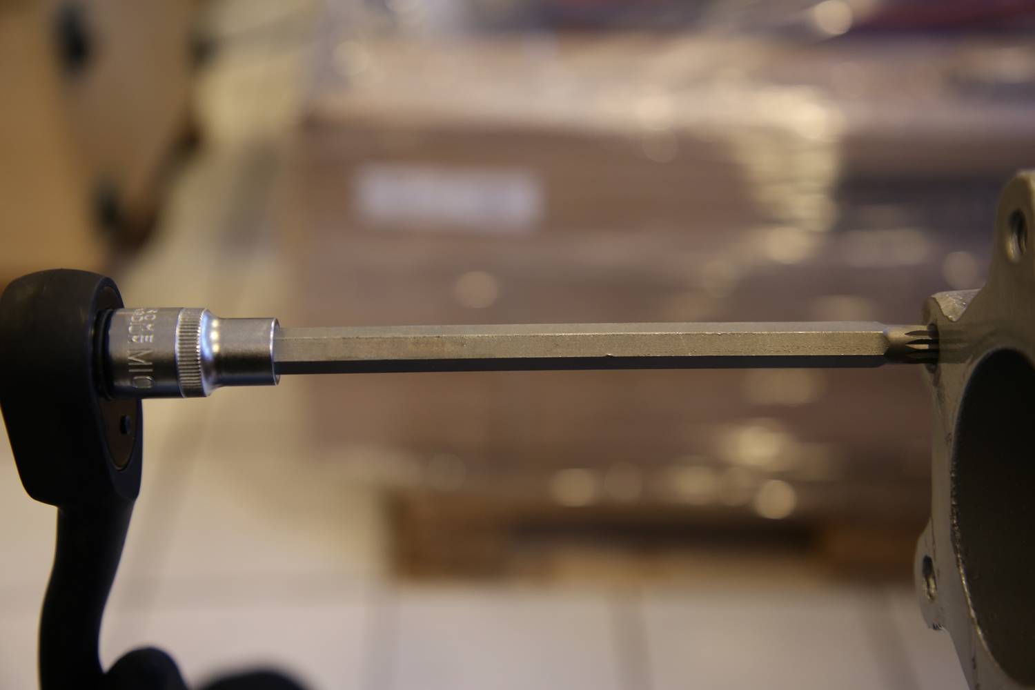 'A long spanner attached to a metal object, with a blurred background of boxes or parcels.'