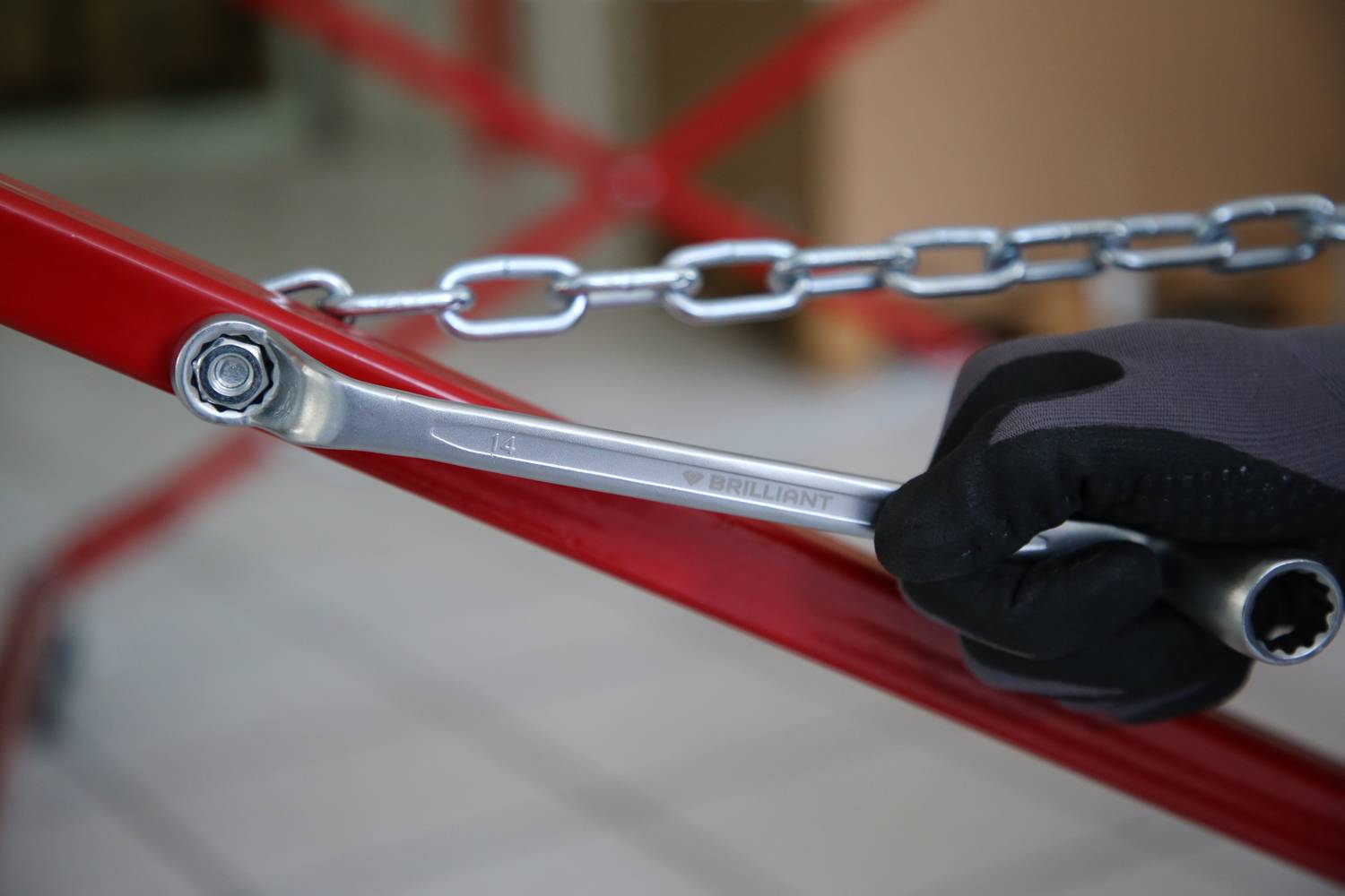 A gloved hand holding a spanner attached to a chain symbolises craftsmanship or repair.