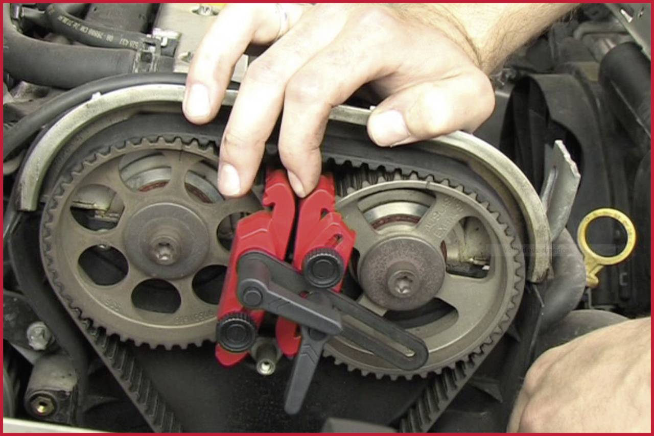 A mechanic is adjusting a timing belt on an engine, using red clamps to stabilise the gears. Focusing on precision and maintenance.