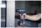 A person holds a blue and black cordless drill near a metal surface inside a modern room, suggesting DIY or home improvement work.