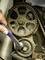A spanner tightens the timing belt of an engine to check and adjust the tension. The focus is on maintenance.