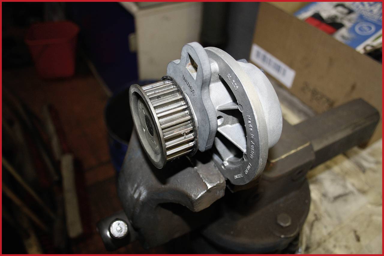 'A mechanical pump unit with a gear wheel, mounted in a workbench holder.'