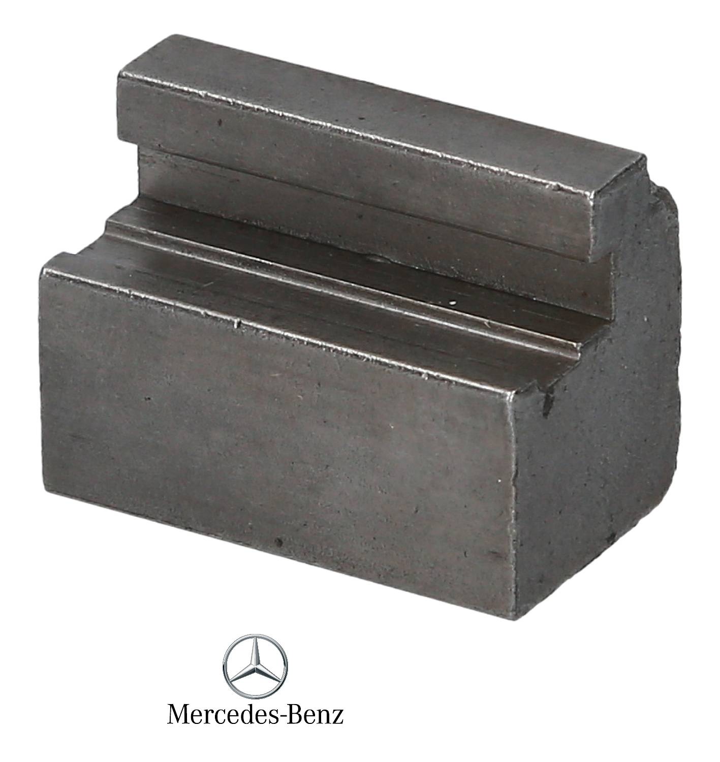 A massive, rectangular metal block with a stepped edge; beneath it the Mercedes-Benz logo.