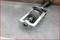 A car component showing a drive shaft is lying on a workbench. It is made of metal and has a joint with several bolts.