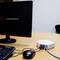 A computer monitor displays a company logo. Next to it, a router with network cables plugged in is visible on a desk.