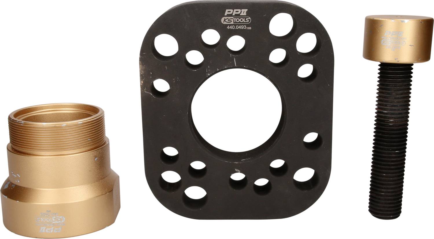 Three metal components for axle mounting: On the left, an adapter, in the middle a disc with holes, on the right a large screw.