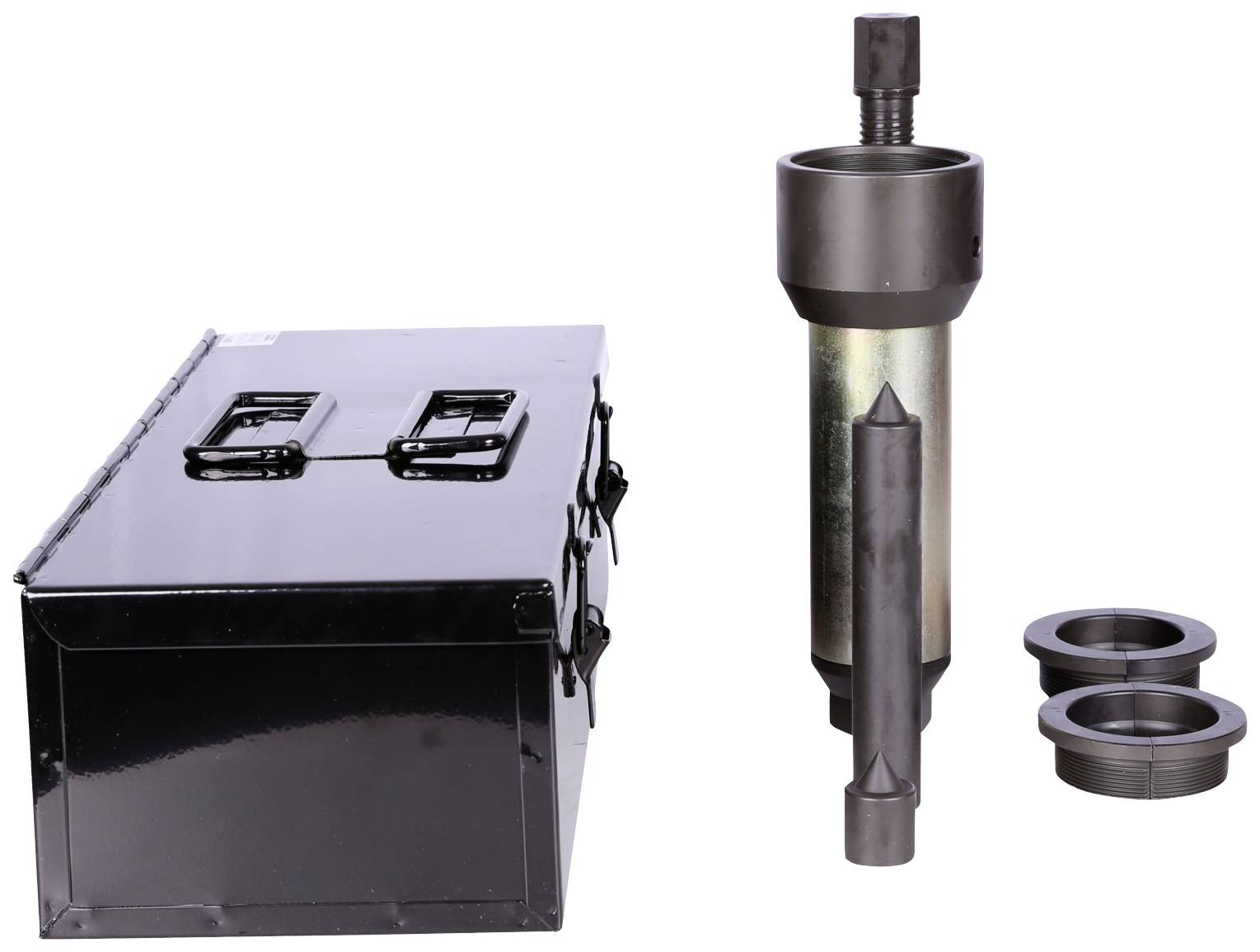 A cylindrical metal tool beside a black box and two metal rings on a white background.