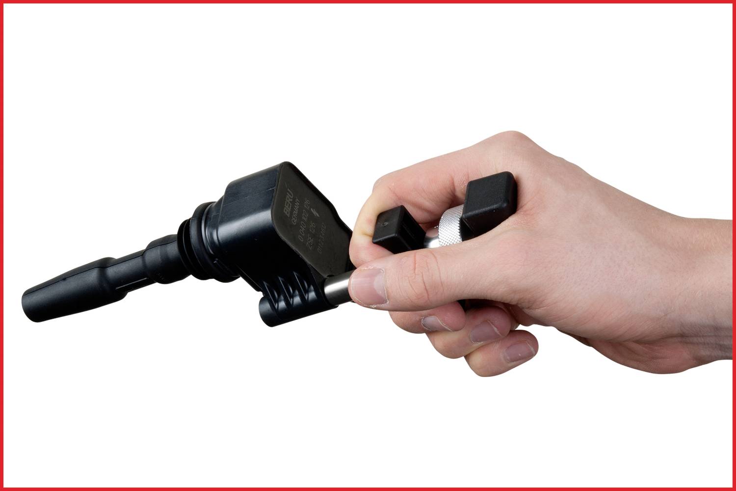 A hand is holding a spark plug socket spanner, which is used for vehicles or machines.