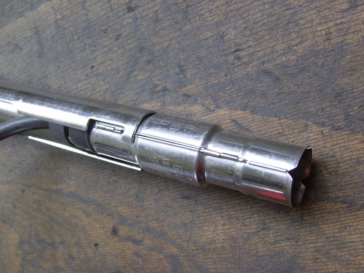 Metal soldering iron on a wooden surface. Ideal for heating and joining metal parts in craft projects.