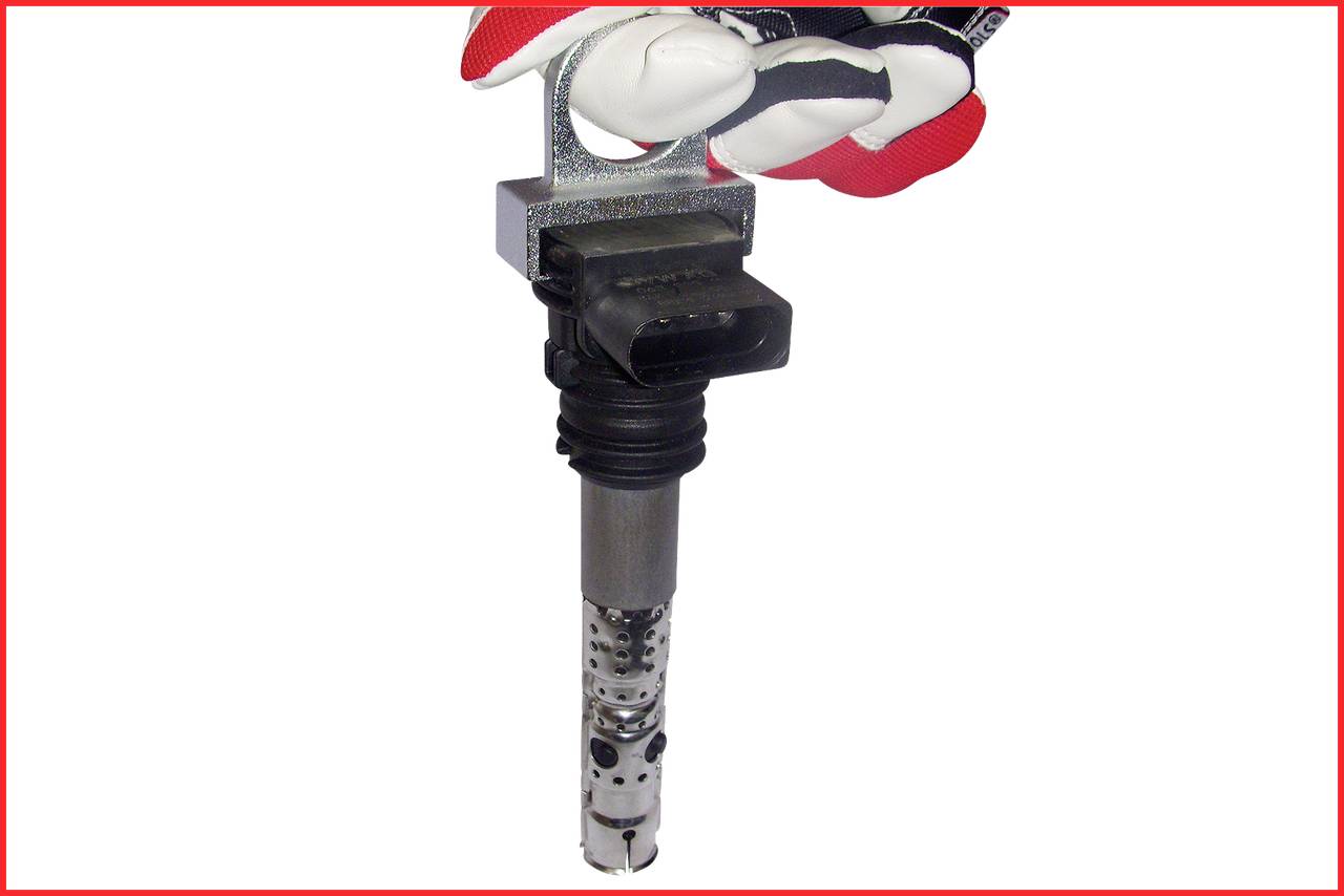 A hand in a glove holds an ignition coil.