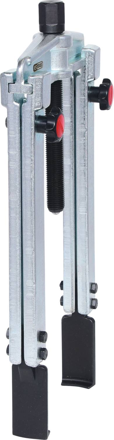 Metallic three-arm puller with red knurled knobs and rubber feet, used for dismantling or maintaining machine parts.