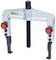 A silver puller with two adjustable arms and red buttons, suitable for removing bearings or gear wheels.