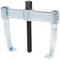 A metallic puller with two hooks and a central screw, used for removing gears or bearings in mechanical devices.