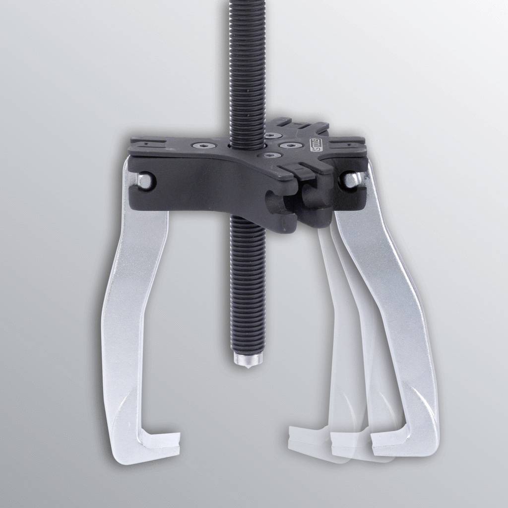 Metallic puller with adjustable gripping arms against a grey background. Usable for removing bearings or gears from shafts.