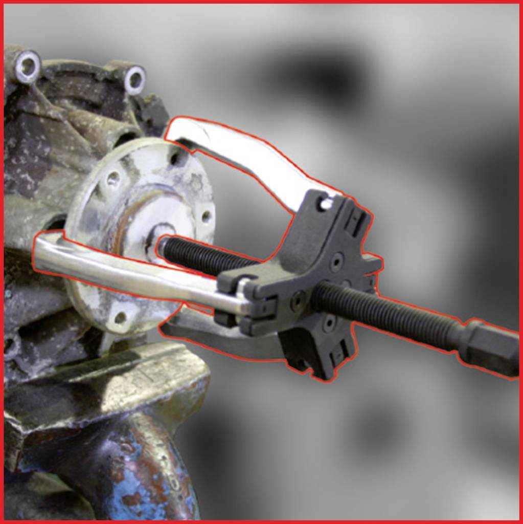 A puller removes a bearing from a machine shaft. The tool has two arms and grips the bearing to pull it out.