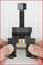 A G-clamp held with two hands, gripping it from below and tightening the screw. It is used to clamp objects firmly.