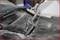 A puller tool is attached to an automotive part to remove it. The car and tool are covered in dust.