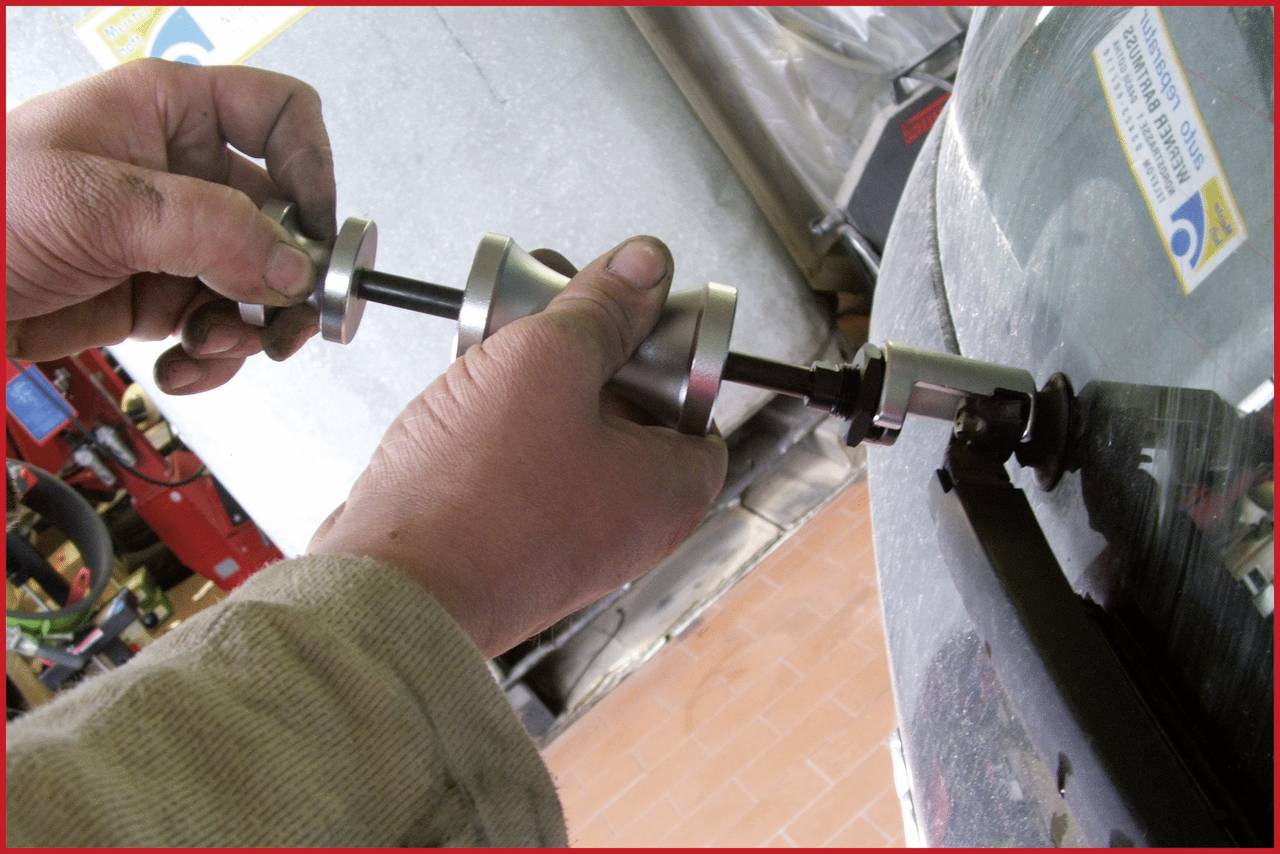A mechanic uses a tool to repair or replace the tyre. Close-up of the hands and tool on the tyre.