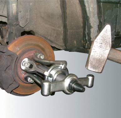 A wheel bearing puller removes a wheel bearing from a vehicle. A hammer on the right is used as a supporting tool.