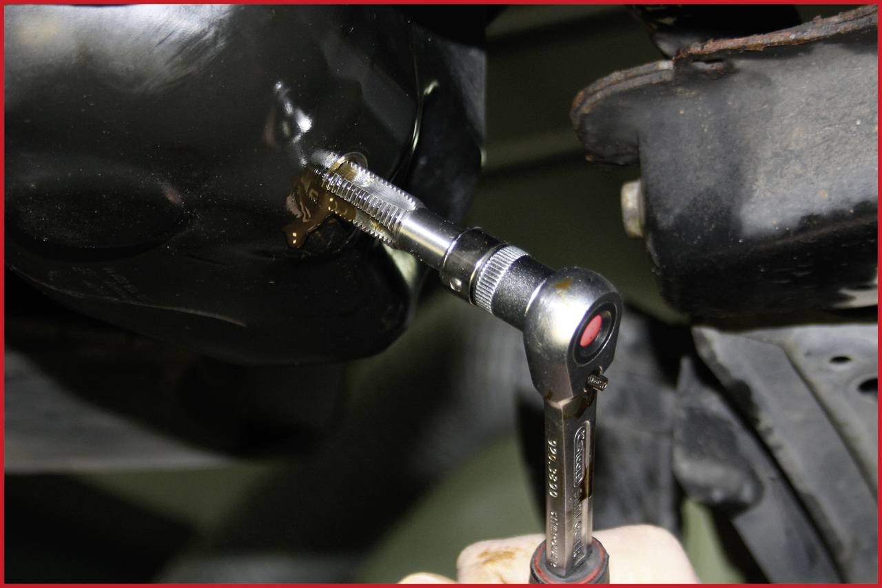 'A ratchet tool is tightening a screw on a black metal component.'