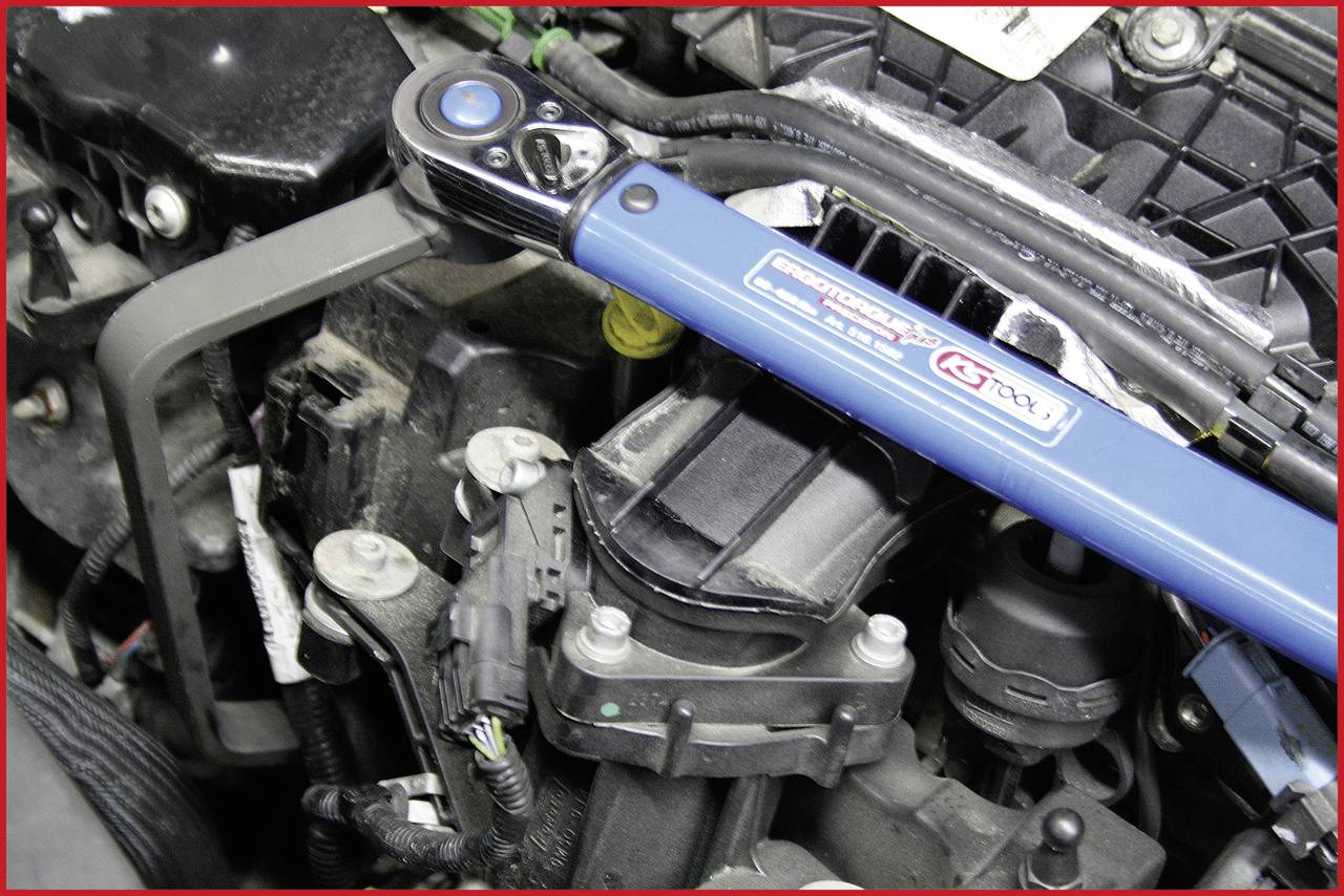 'Torque wrench attached to engine block, blue tool enables precise tightening of bolts and nuts to specified torque.'
