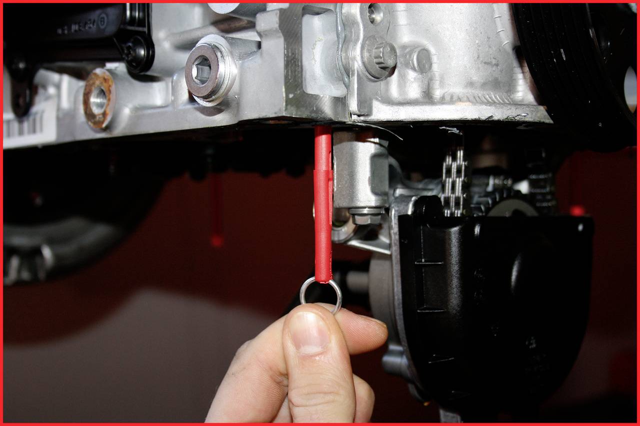 'A hand pulls out the oil dipstick of an engine.'