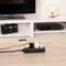 A charging cable is connected to a power strip on a table, next to a smartphone and an illuminated table lamp base.