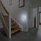 Entrance hall of a house with a staircase and corridor, modern decor and a wall light casting a soft glow.