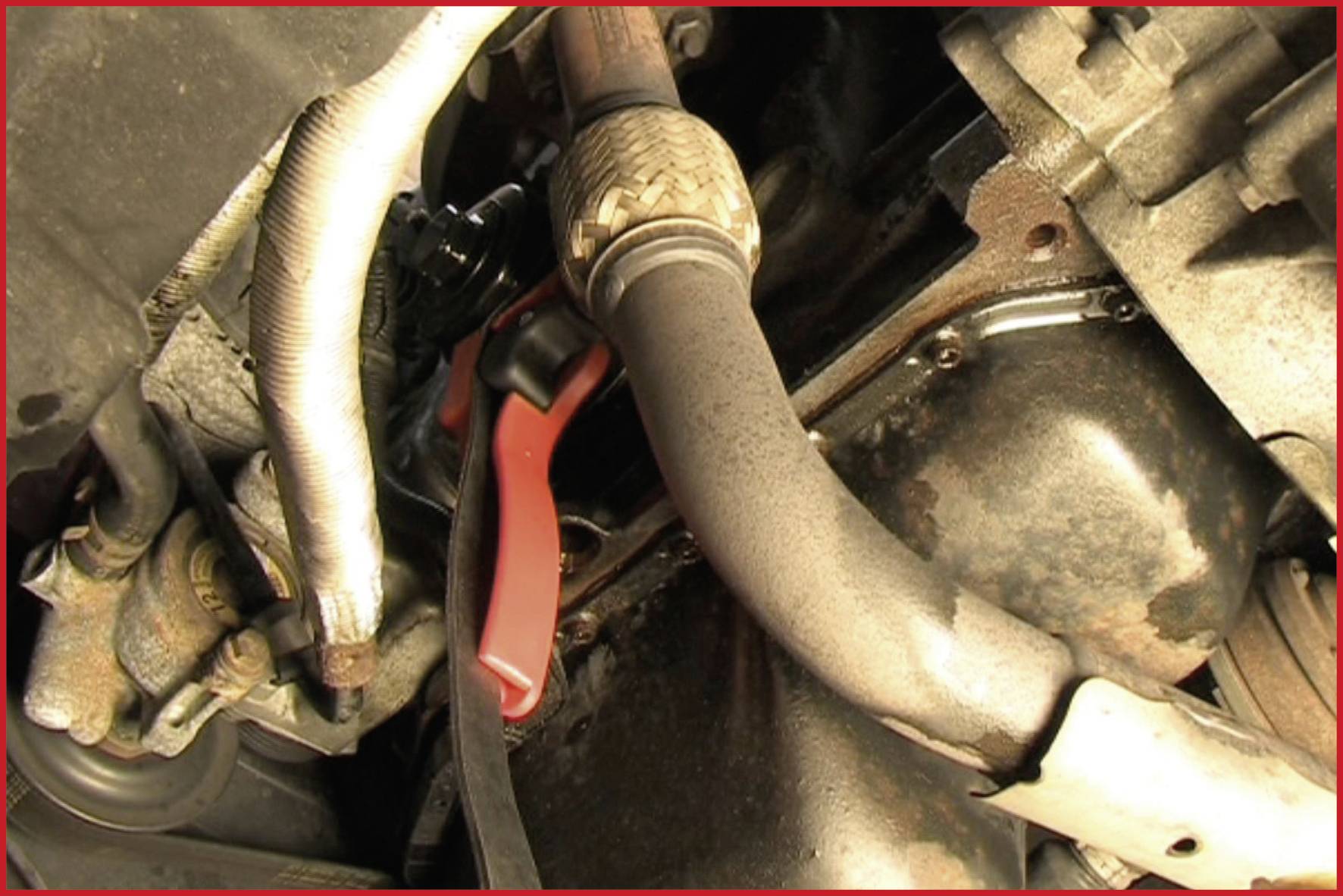 Motor with various pipes and connective components in a vehicle engine. Predominantly rusty parts visible.