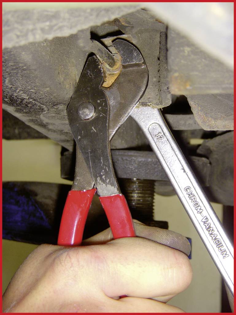 A hand is holding a red pipe wrench gripping a metal part, while a spanner marked 'Chrome Vanadium' secures the component.