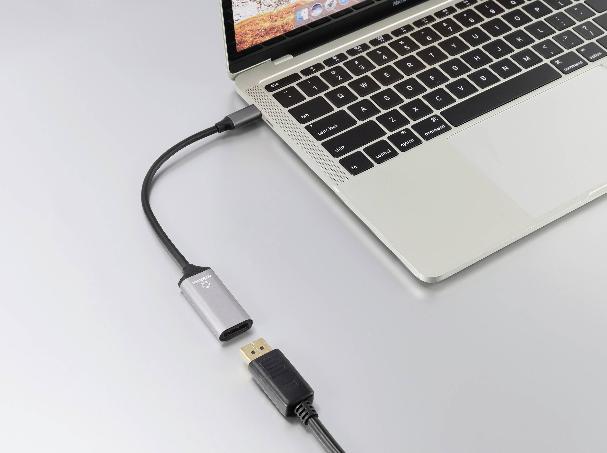 A laptop with an open display is connected via an HDMI cable to a USB-C adaptor.
