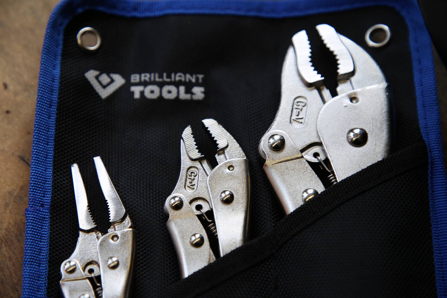 Three silver pliers in a blue bag with the inscription 'Brilliant Tools', placed on a wooden surface. They display different plier sizes.