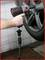 A person is securing a car tyre with an impact wrench in a workshop. The tyre is mounted on a vehicle lift.