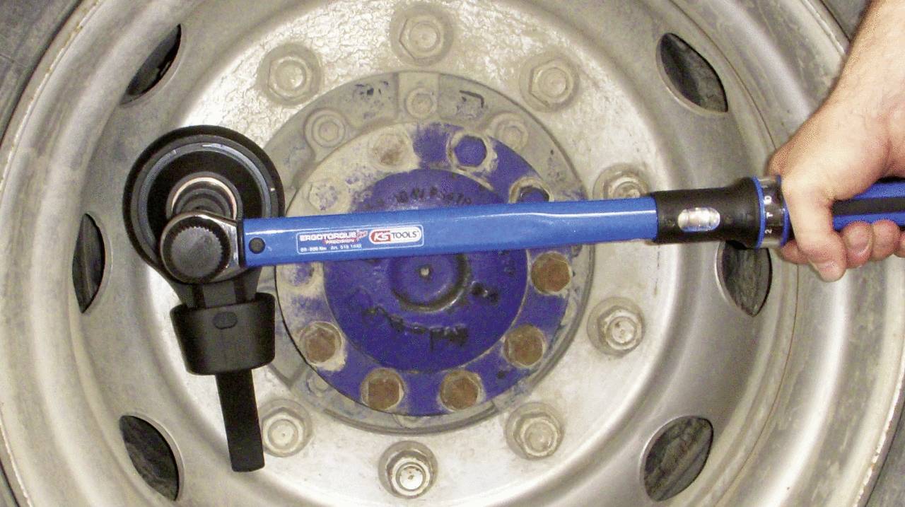 A torque wrench tightens the wheel nuts of a lorry wheel to ensure a secure fastening.
