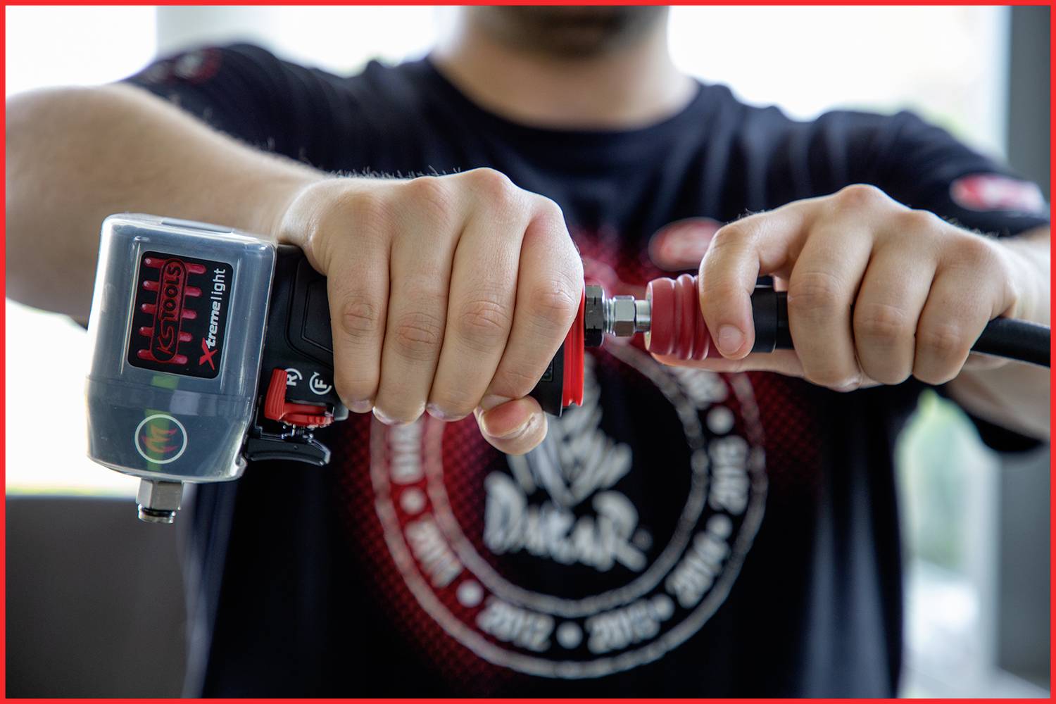 A person is connecting an air hose with a tool in a workshop, focusing on the hands and the connection.