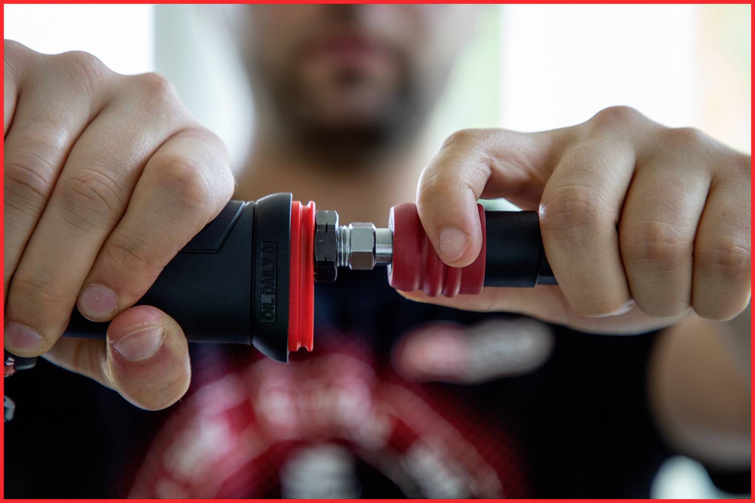 'Close-up of a person screwing a red locking nut onto a black pipe. Focus on the hands and the connection.'