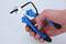A hand is holding a blue side cutter that is cutting through a black cable.