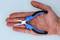 A hand is holding a small pair of pliers with blue handles, which are useful for precision mechanical work.
