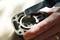 A hand is holding a metal part while a screwdriver is used to adjust a component inside.