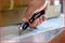A hand holds a black utility knife and cuts the plastic film around a cardboard box.