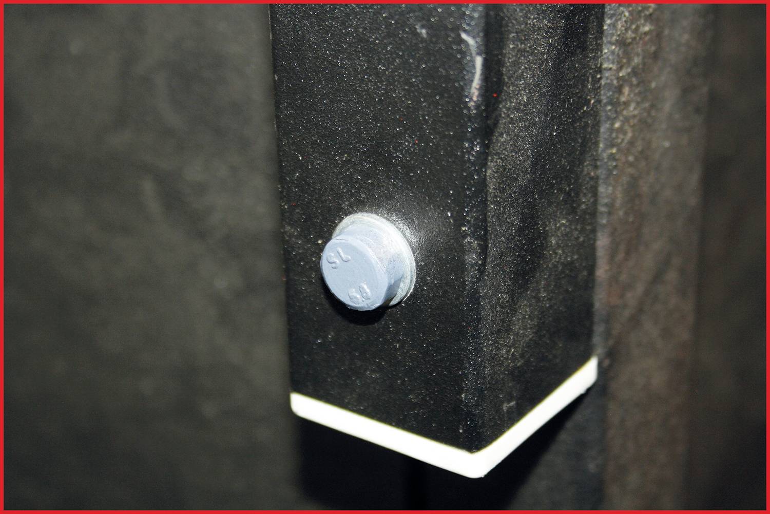 Close-up of a screw in a black metal plate, which appears to be connecting part of a structural element.