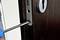 A close-up shows a person screwing a screw into a door lock with a screwdriver.