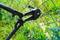 A bolt cutter is cutting through a green wire mesh fence in a garden area.