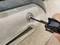 'A person is tightening a screw on a metallic object with a black tool.'
